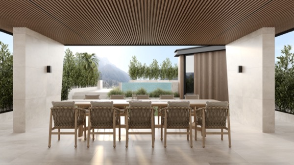 Überdachte Terrasse mit langem Esstisch aus Holz, Geflechtstühlen, Lamellendecke, Pool und Bergpanorama